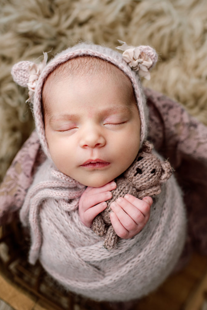 Portrait of newborn girl in bear bonnet holding teddy bear in St. Augustine, FL