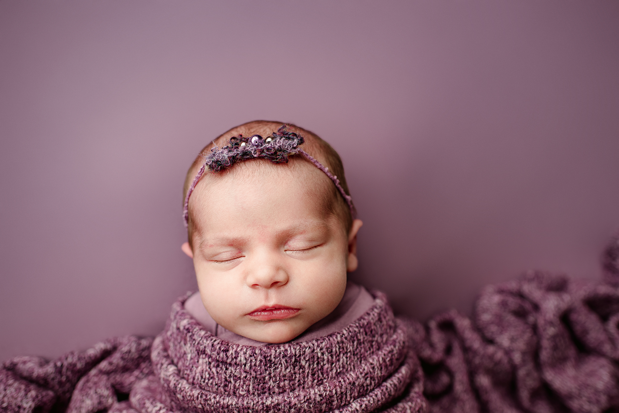 Studio image of baby girl in purple wrap with headband in St. Augustine, Florida.