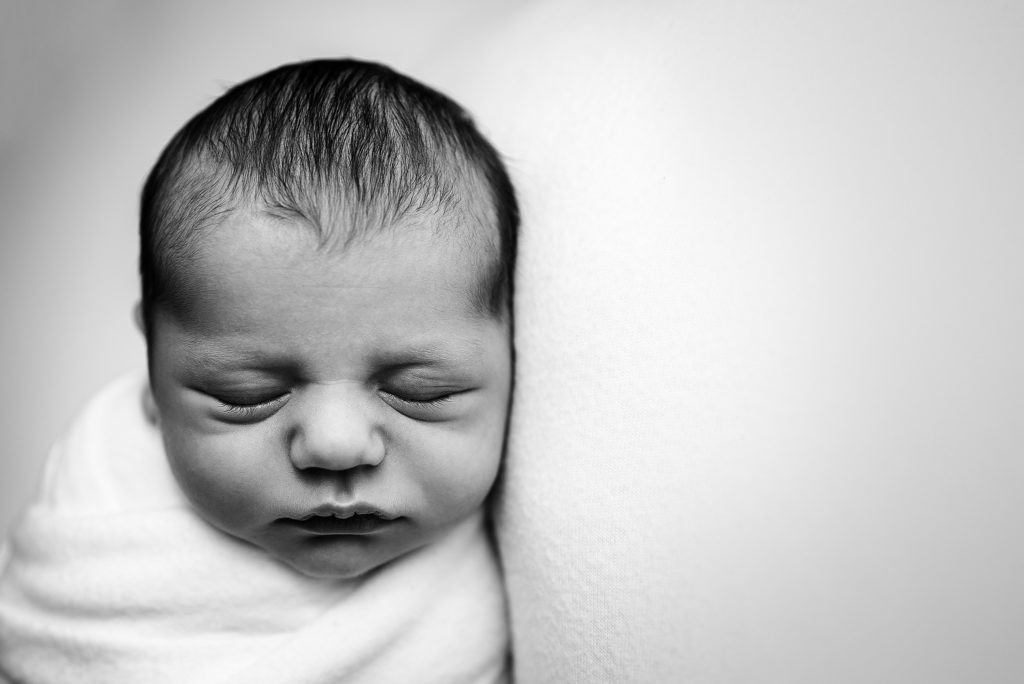 Close up studio image in black and white of swaddled newborn boy in Ponte Vedra, FL.