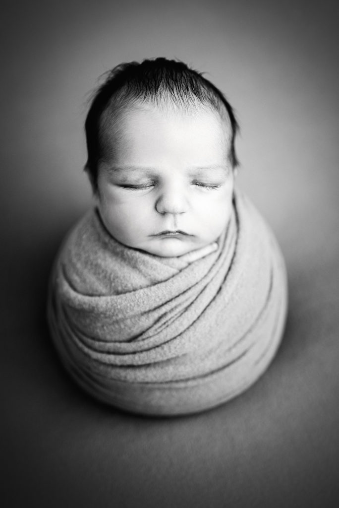 Black and white photo of baby boy wrapped in potato pose in Atlantic Beach, FL.
