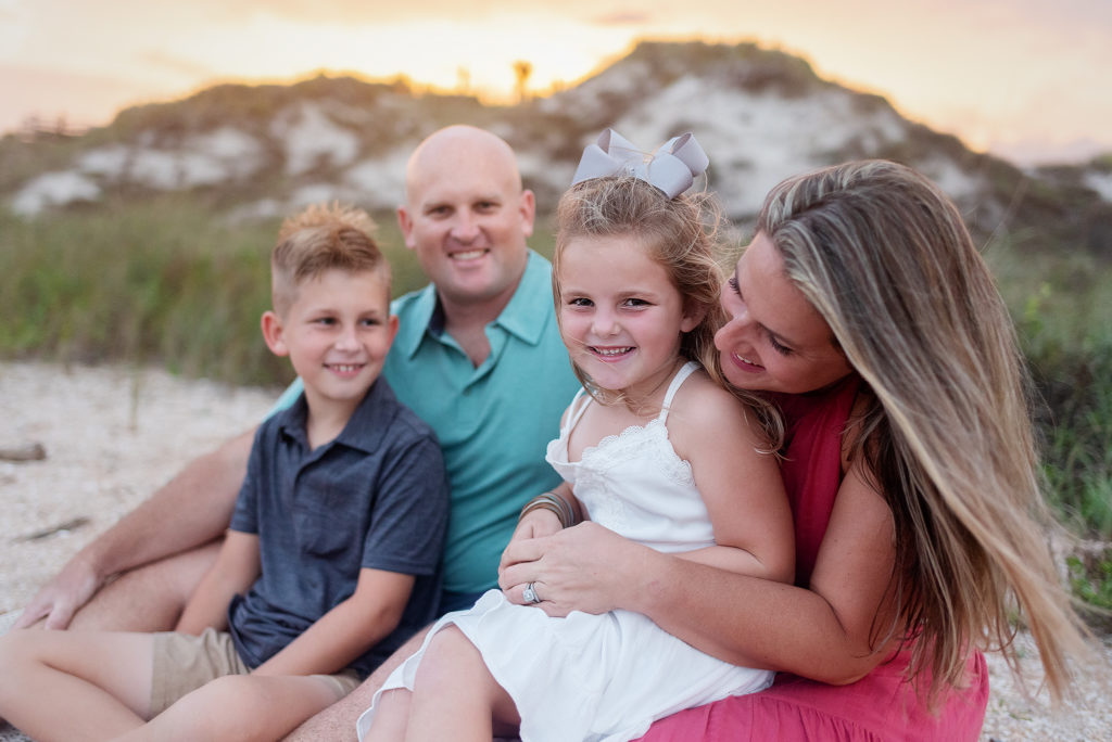 Family of 4 in blues and pinks with boy girl siblings smiling and laughing in Guana Reserve Beach, Ponte Vedra, Florida.