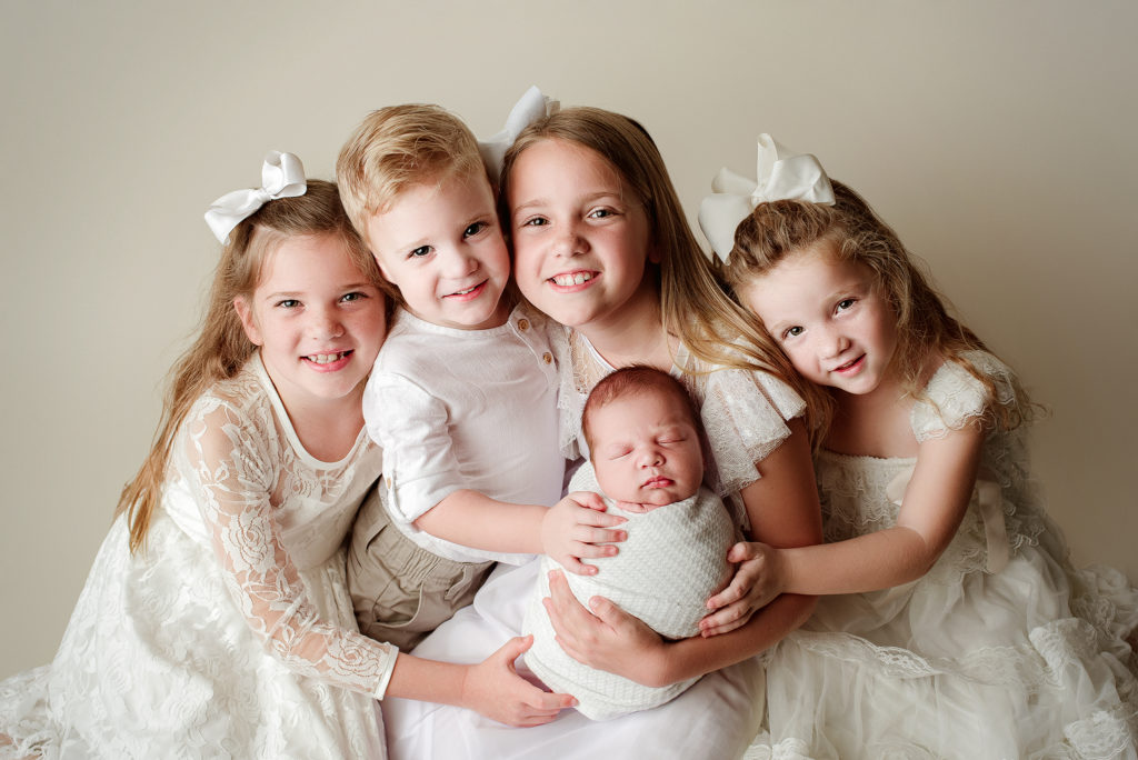 Sibling group of 5 including newborn brother dressed in neutrals for studio session in Jacksonville, FL.